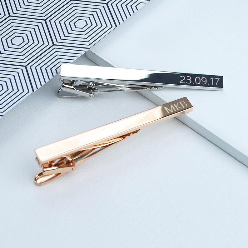 Personalised tie clip shown in silver(rhodium plated) and rose gold plated finishes with engraved initials and a date.