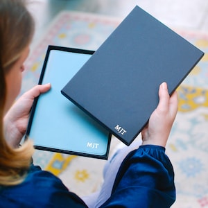 May include: A blue leather journal with the initials "M.J.T." embossed on the cover, inside a navy blue gift box with the same initials.
