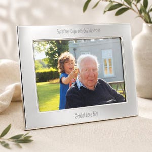 Può includere: Una cornice fotografica rettangolare argentata con una foto di un uomo e un bambino. La cornice presenta il testo "Sunshiney Days with Grandad Pops" in alto e "Gotcha! Love Billy" in basso.