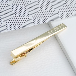 Personalised tie clip shown in gold plated finish showing date engraved in script play font choice.