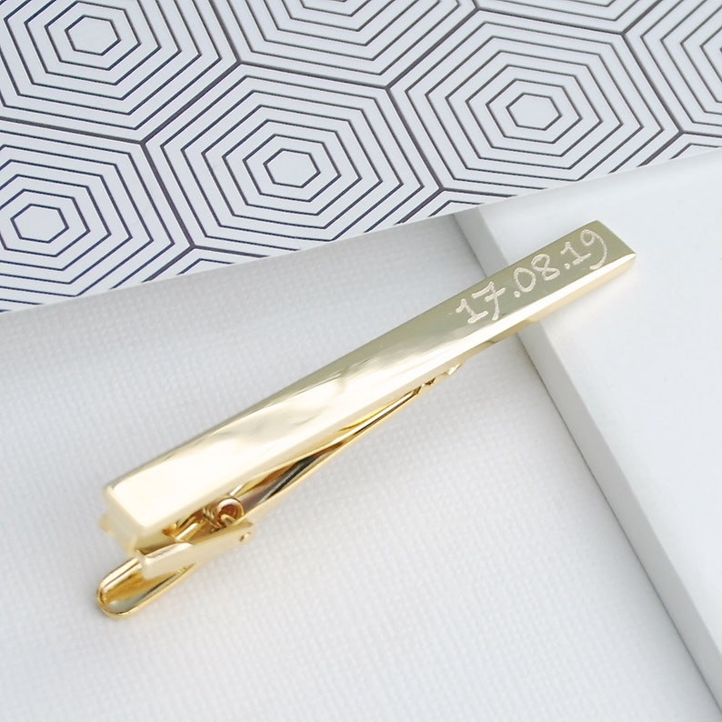 Personalised tie clip shown in gold plated finish showing date engraved in script play font choice.