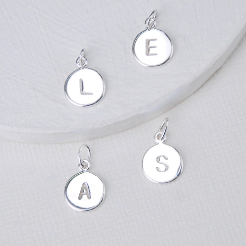 New style Sterling Silver initial letter disc charms shown close up.
