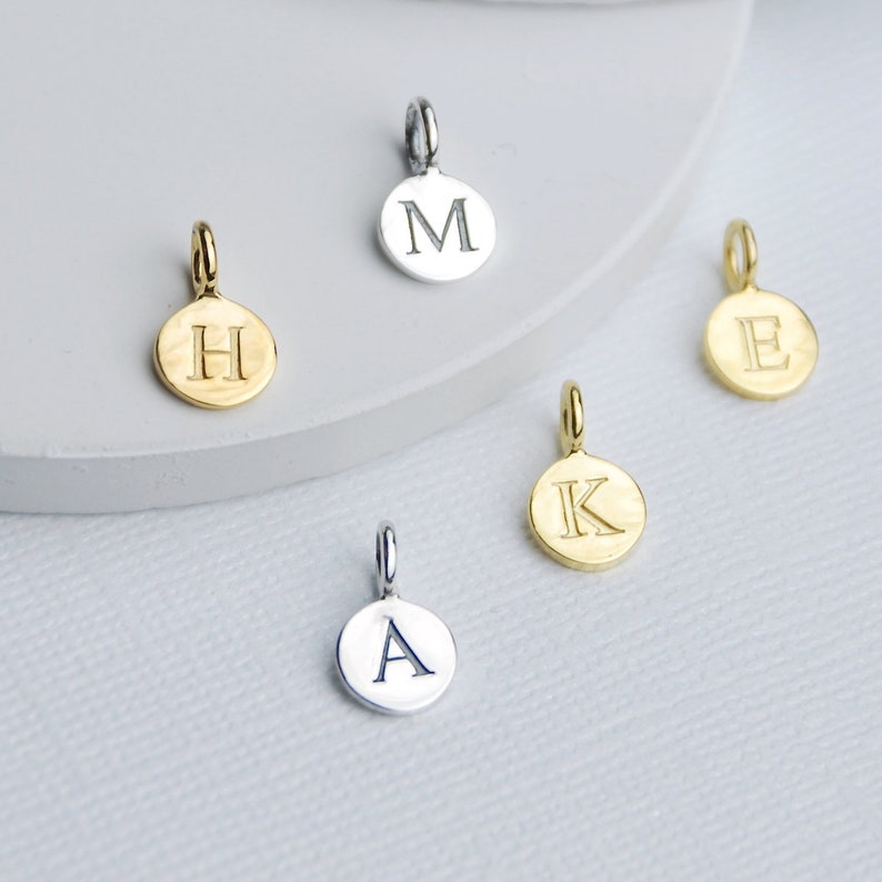 Sterling Silver and Gold plated sterling silver initial letter disc charms shown close up.