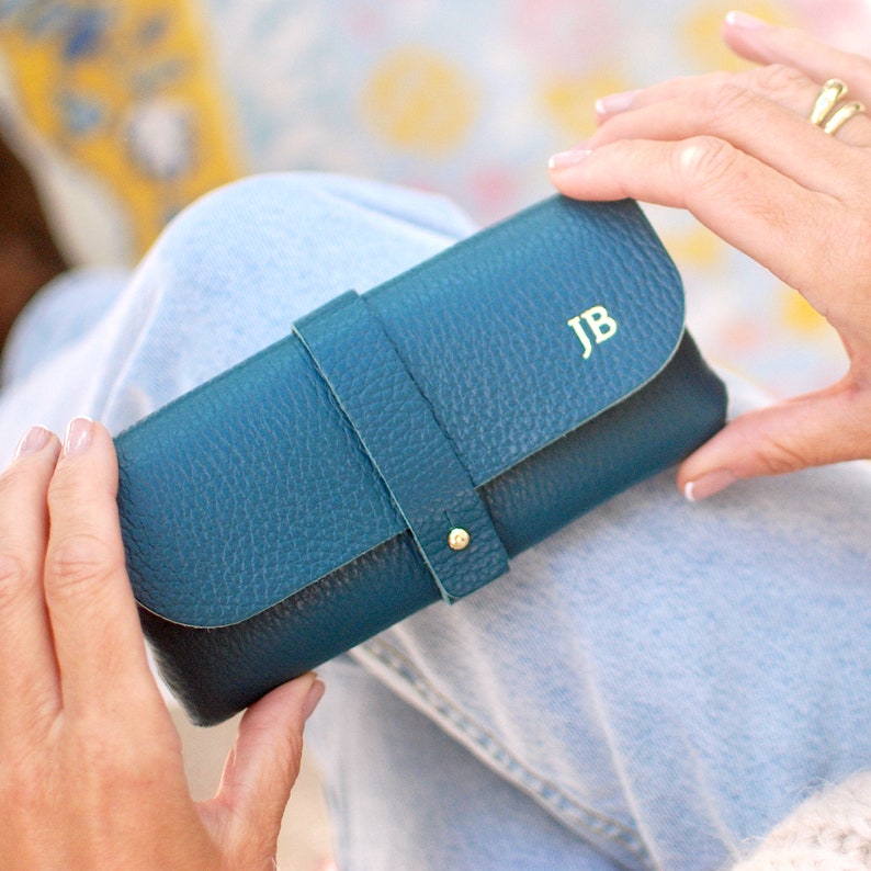 Teal Personalised Leather Glasses case shown close up with model with JB monogram in gold.