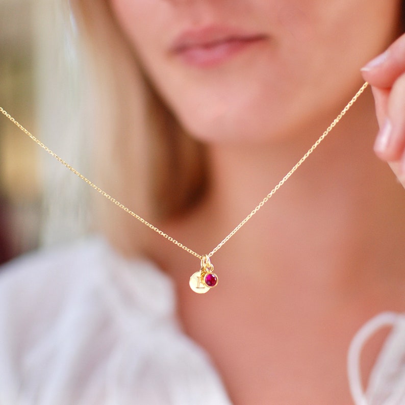 Personalised Gold Initial Birthstone necklace on 18 inch chain shown close up with model holding it.