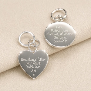 May include: Two silver keyrings, one heart-shaped and one circular. The heart keyring has the inscription "Em, always follow your heart. With love Abi x". The circular keyring reads "Lou, Follow your dreams, it knows the way. Sophie x".