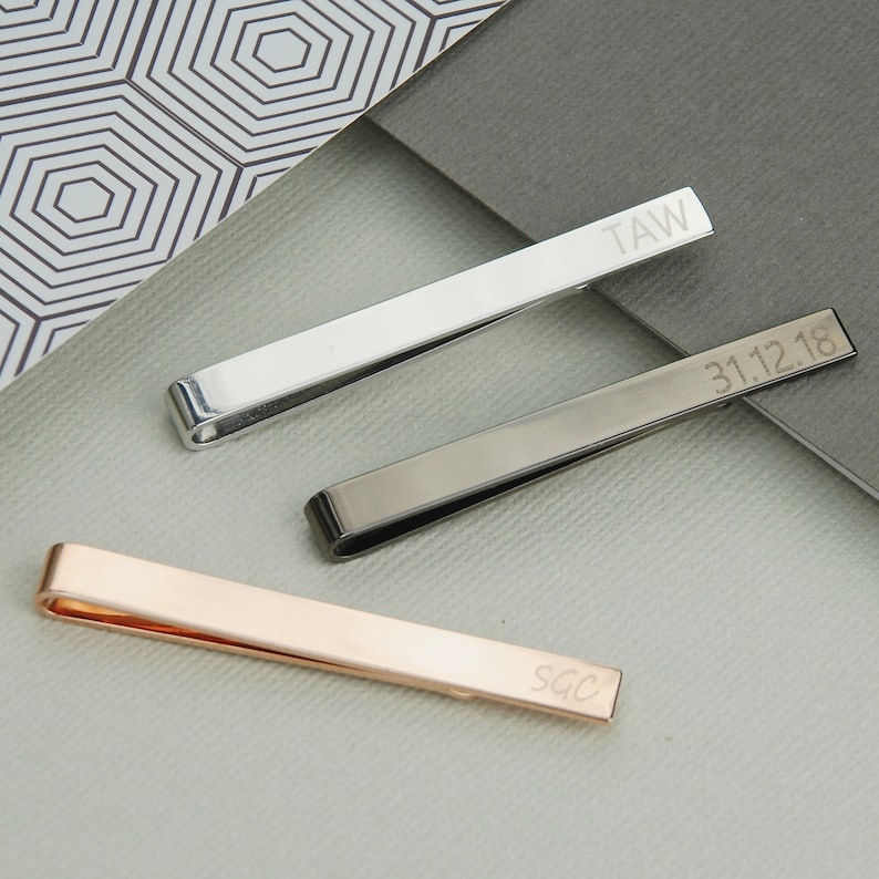 Personalised Tie Slide shown in rose gold, gunmetal and silver/rhodium plated finishes with engraving on front and back.