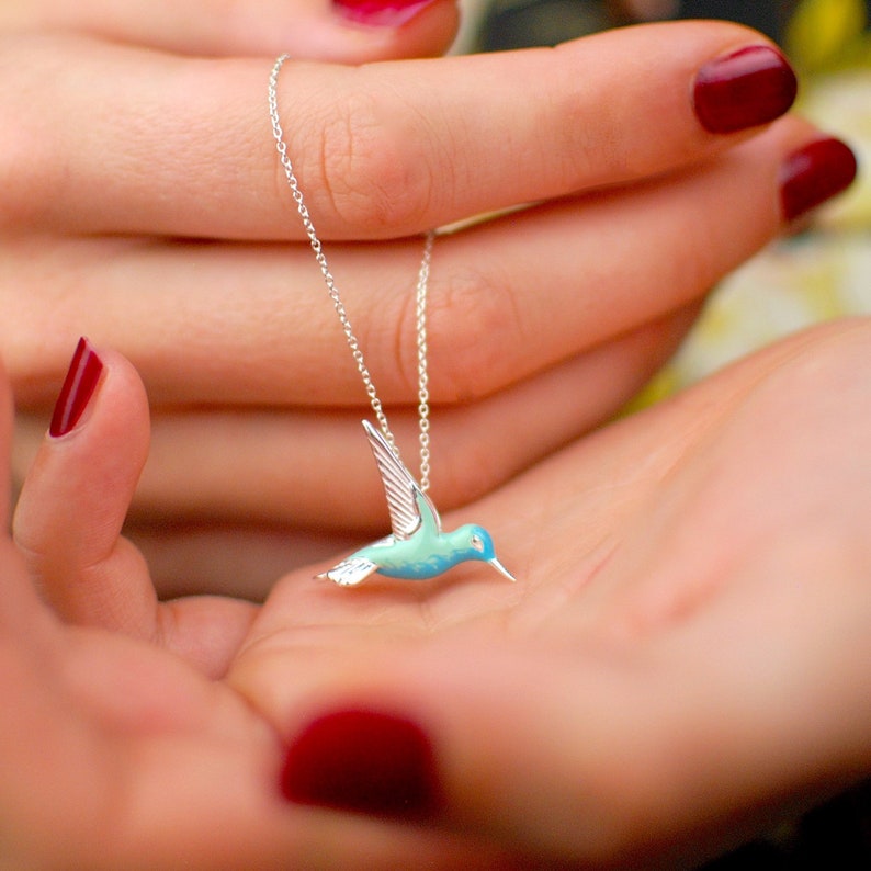 Sterling Silver and Enamel Hummingbird Necklace shown in close up on models hand.