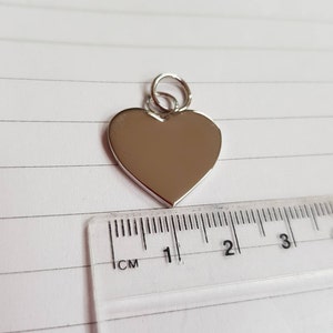 Silver heart charm with ruler to show size. The heart charm is 20mm wide
