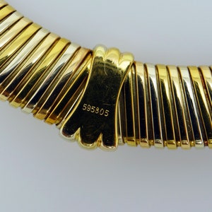 May include: A gold, silver, and rose gold necklace with a clasp that has the number 595805 engraved on it.