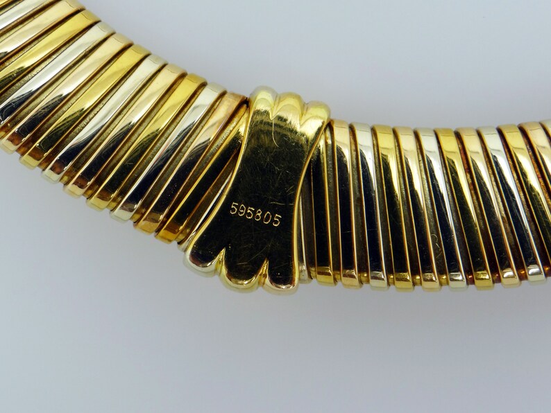May include: A gold, silver, and rose gold necklace with a clasp that has the number 595805 engraved on it.