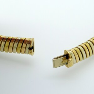 May include: A gold, silver, and rose gold necklace with a clasp. The necklace is made of a series of interlocking rings.