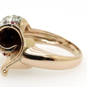 May include: A gold ring with a red and white stone set in a swirl design. The ring is marked "14K PLAT" on the inside of the band.