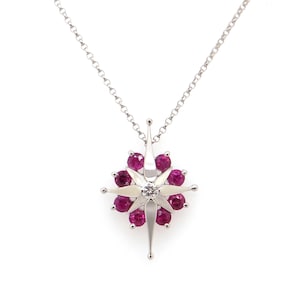 May include: A silver necklace with a star-shaped pendant. The pendant is adorned with red rubies and a single white diamond in the center.