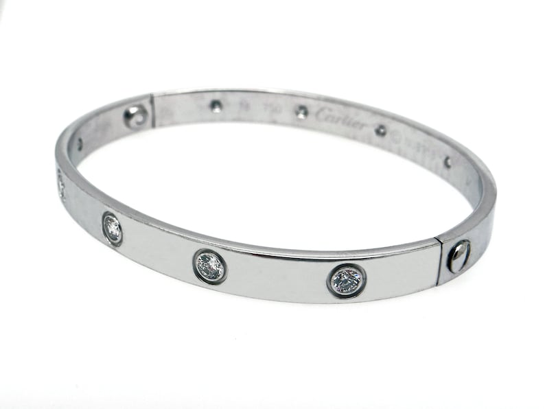 May include: A silver Cartier Love bracelet with five round diamonds set into the band. The bracelet is engraved with the Cartier logo and '750' on the inside.