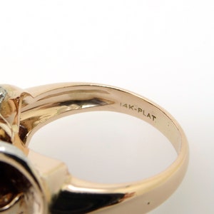 May include: Close-up of the inside of a gold ring with the inscription "14K-PLAT" on the band.