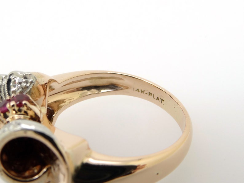 May include: Close-up of the inside of a gold ring with the inscription "14K-PLAT" on the band.