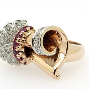 May include: A gold ring with a swirl design set with rubies and diamonds. The ring is made of 14k gold and features a unique design.