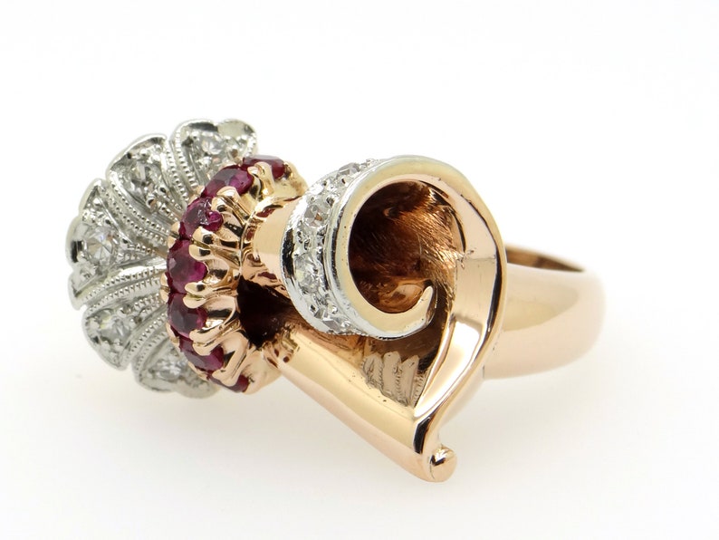 May include: A gold ring with a swirl design set with rubies and diamonds. The ring is made of 14k gold and features a unique design.