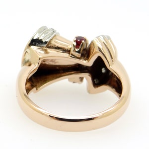 May include: A gold ring with a red gemstone and smaller white gemstones. The ring is set in a twisted design.