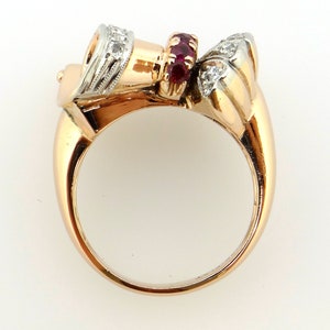 May include: A gold ring with a ruby and diamond setting. The ring is made of two-toned gold, with a white gold band and a rose gold setting. The setting features a cluster of rubies in the center, surrounded by a halo of diamonds.