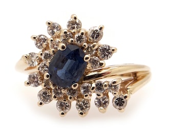May include: A gold ring with a large blue sapphire surrounded by smaller diamonds.