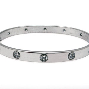 May include: A silver bangle bracelet with a row of clear round stones set into the band.