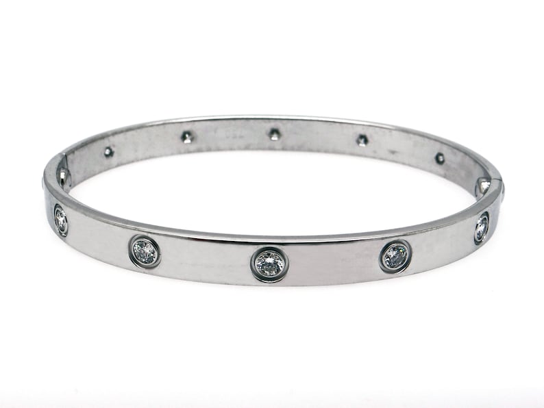 May include: A silver bangle bracelet with a row of clear round stones set into the band.