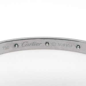 May include: A silver Cartier Love bracelet with diamonds engraved with 'Cartier', '18 750', '© NU8958', and 'IV'.