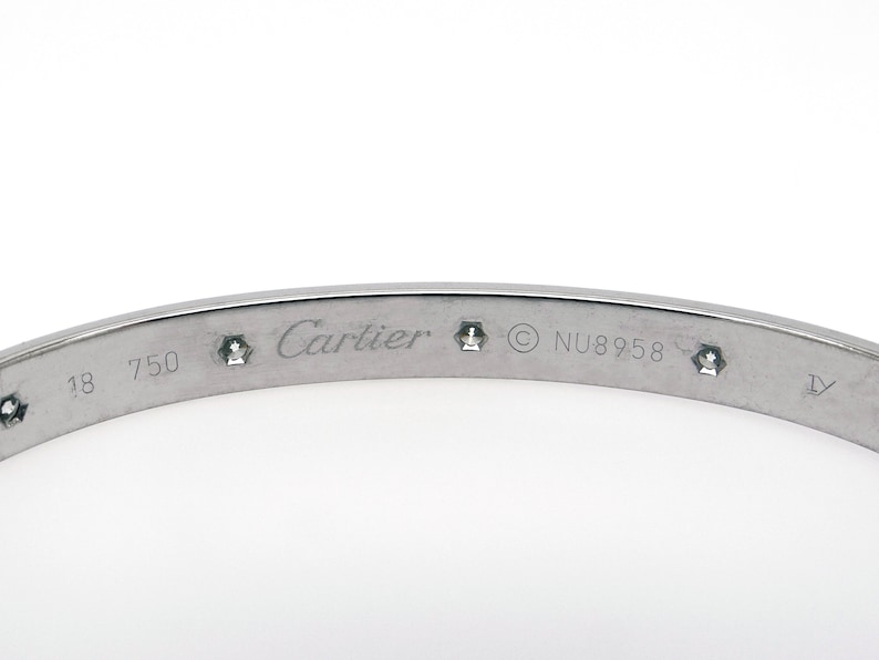 May include: A silver Cartier Love bracelet with diamonds engraved with 'Cartier', '18 750', '© NU8958', and 'IV'.