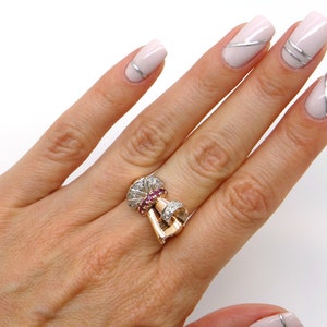 May include: A gold ring with a large, ornate design featuring a cluster of pink gemstones surrounded by smaller white gemstones.