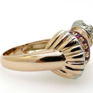May include: A gold ring with a red ruby and white diamond setting. The ring is made of two-toned gold, with a rose gold band and a white gold setting.