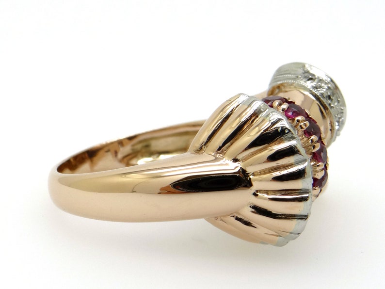 May include: A gold ring with a red ruby and white diamond setting. The ring is made of two-toned gold, with a rose gold band and a white gold setting.