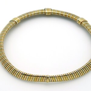 May include: A gold and silver necklace with a flexible, snake chain design.