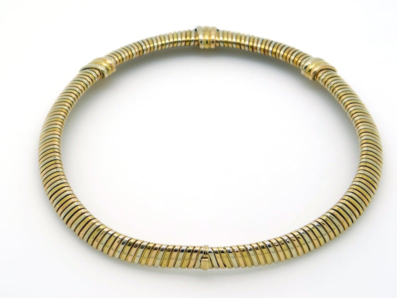 May include: A gold and silver necklace with a flexible, snake chain design.