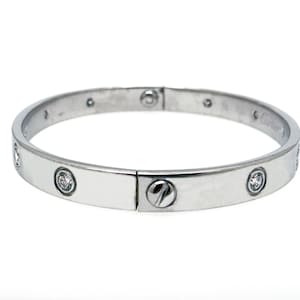 May include: A silver bangle bracelet with a screw-on clasp and small diamonds set around the band.