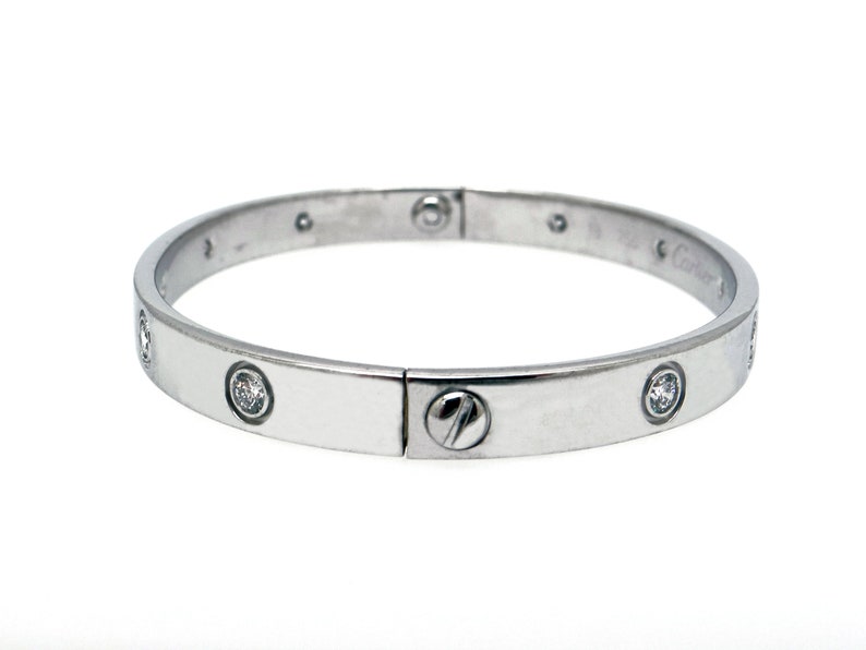 May include: A silver bangle bracelet with a screw-on clasp and small diamonds set around the band.