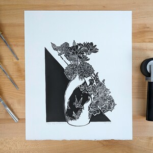Linoleum block print of floral bouquet surrounded by carving and inking tools.