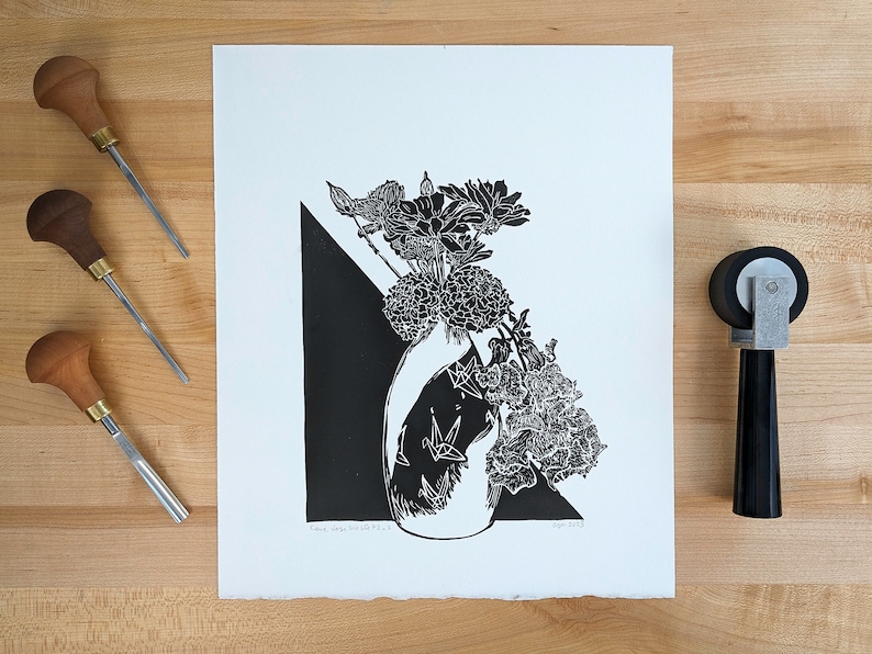 Linoleum block print of floral bouquet surrounded by carving and inking tools.