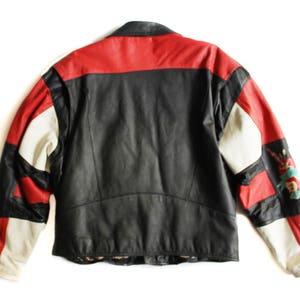 May include: A black leather jacket with red and white panels. The jacket has a zipper closure and a stand-up collar.