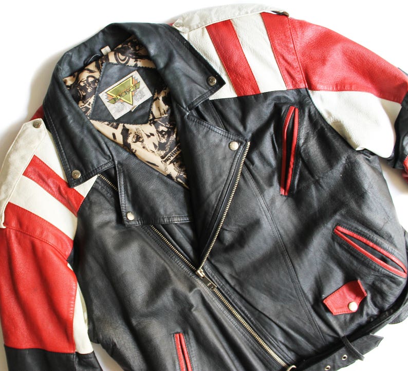 May include: A black leather jacket with red and white striped sleeves. The jacket has a zipper closure and a belt at the waist. The label on the jacket reads "Backlot".