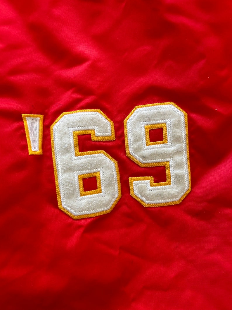 May include: Red fabric with a white and yellow embroidered patch that says '69'.