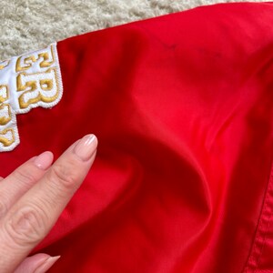 May include: Red satin jacket with a white and gold embroidered patch that says "52" on the left shoulder.
