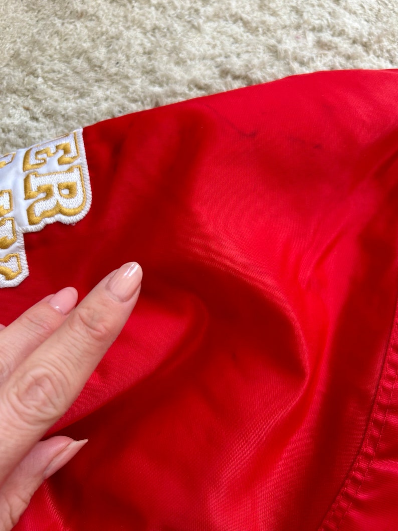 May include: Red satin jacket with a white and gold embroidered patch that says "52" on the left shoulder.