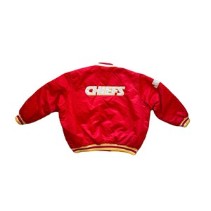 May include: Red satin bomber jacket with a white "CHIEFS" logo on the back. The jacket has yellow and white stripes on the cuffs and waistband.