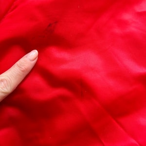 May include: A close-up of a red fabric with a few dark stains.