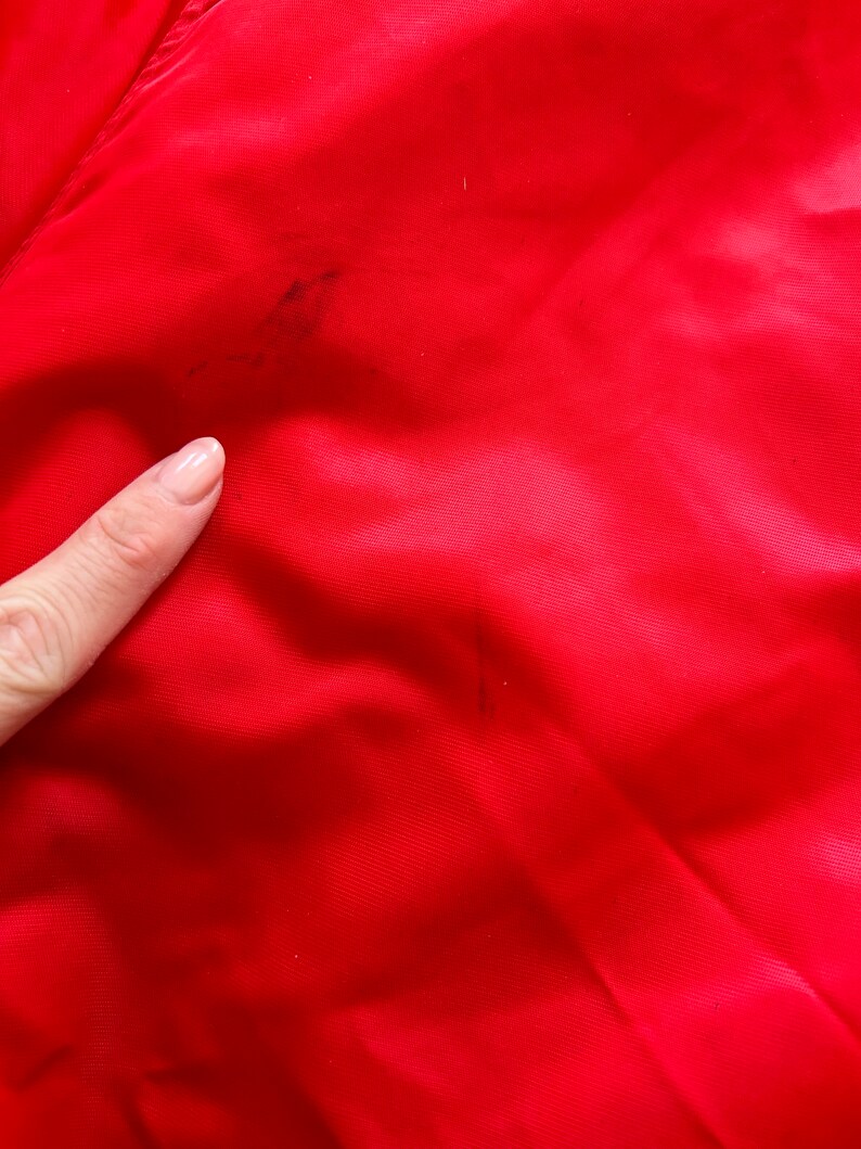 May include: A close-up of a red fabric with a few dark stains.