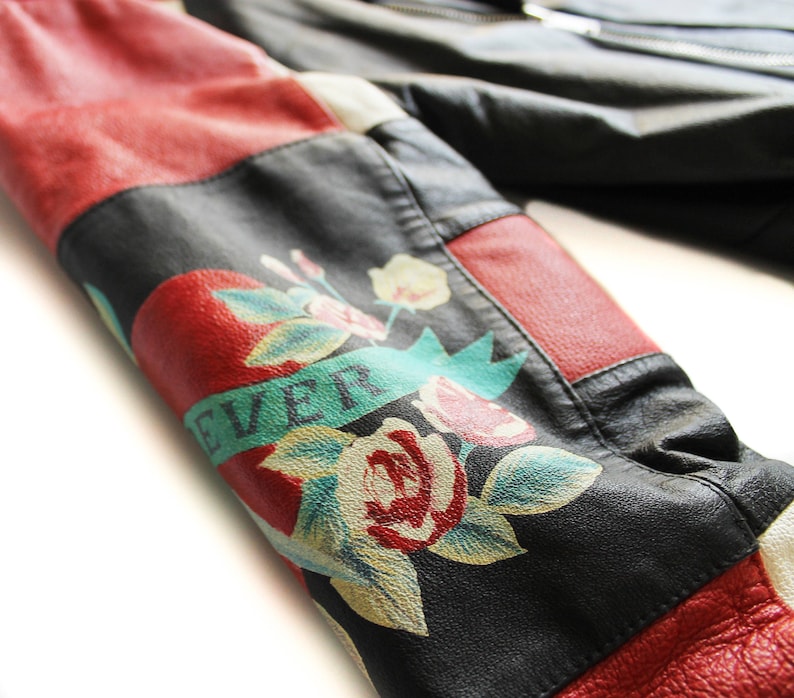 May include: A black leather jacket with red and white panels. The jacket has a floral design with the word "EVER" on the sleeve.