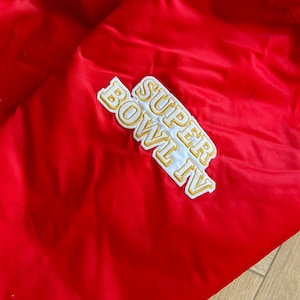 May include: Red jacket with a white and gold embroidered patch that says "SUPER BOWL IV".