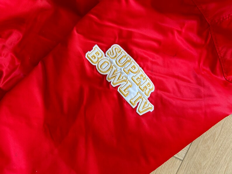 May include: Red jacket with a white and gold embroidered patch that says "SUPER BOWL IV".